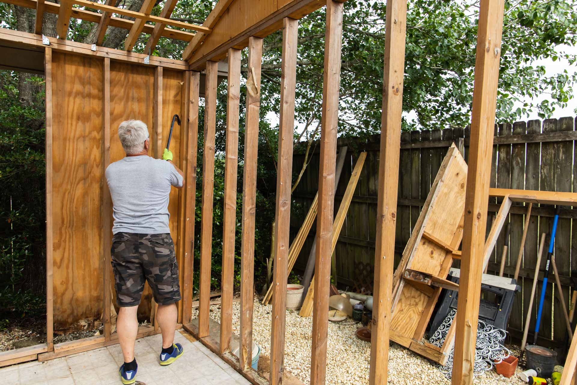 Man tearing down shed with crowbar